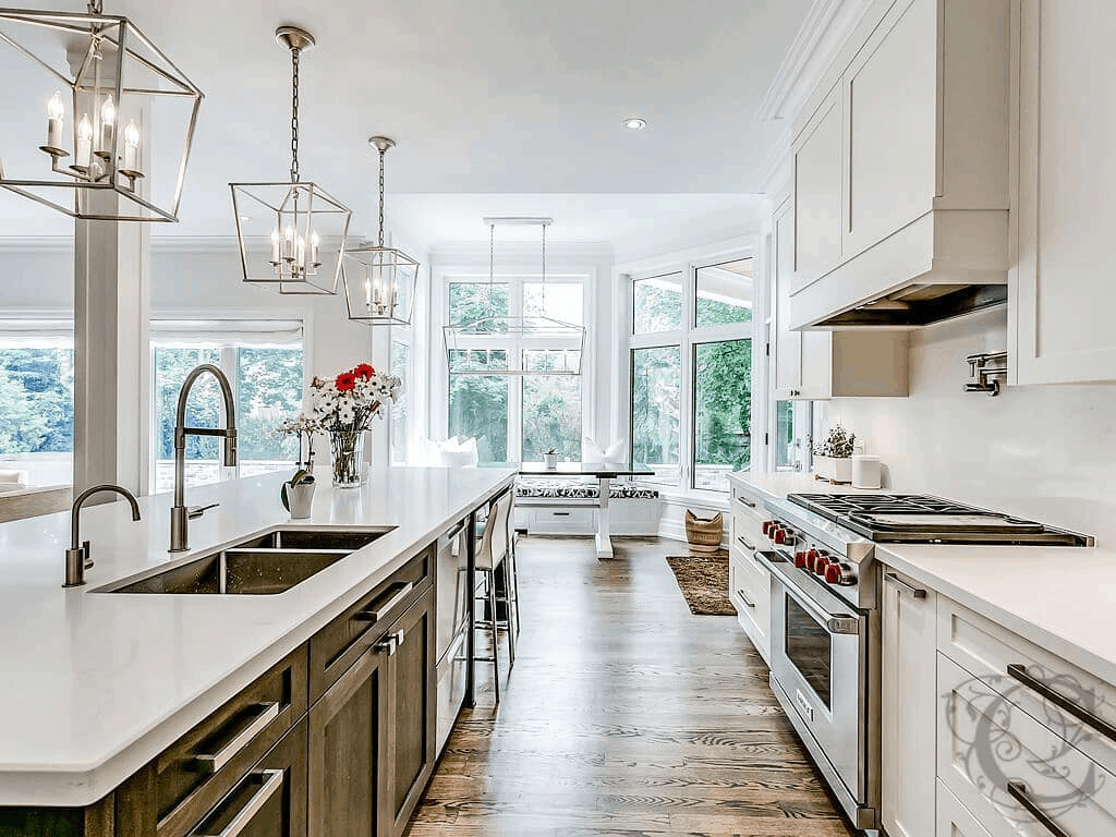 A large kitchen with white cabinets and hardwood floors is a feature of the Burlington home builders' newly constructed houses.