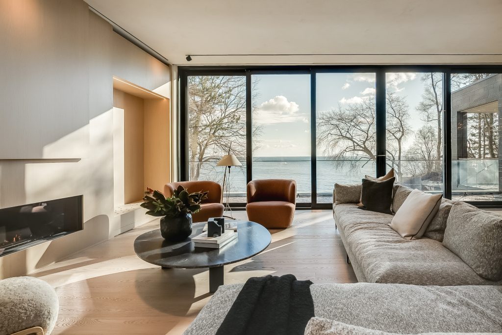 A modern living room with large windows overlooking the lake, showcasing modern design trends.