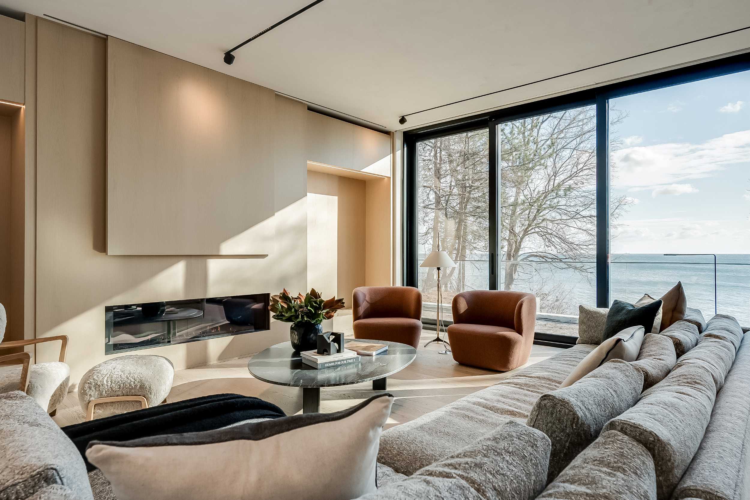 A modern living room with large windows overlooking the West Oakville lakefront, luxury custom home