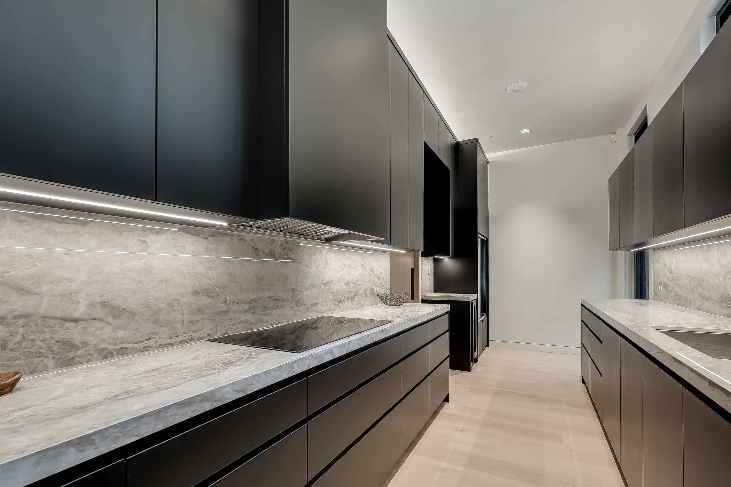 A modern kitchen with black cabinets and marble counter tops in a west oakville lakefront home.